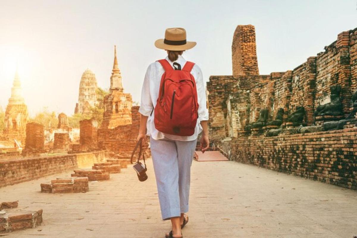uma mulher com uma mochila vermelha caminhando por um templo