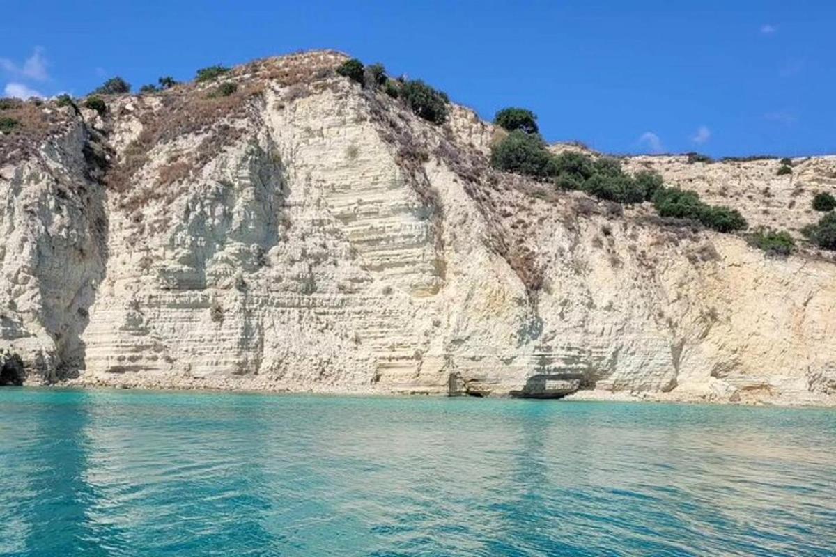 a rocky cliff with the blue water in front of it
