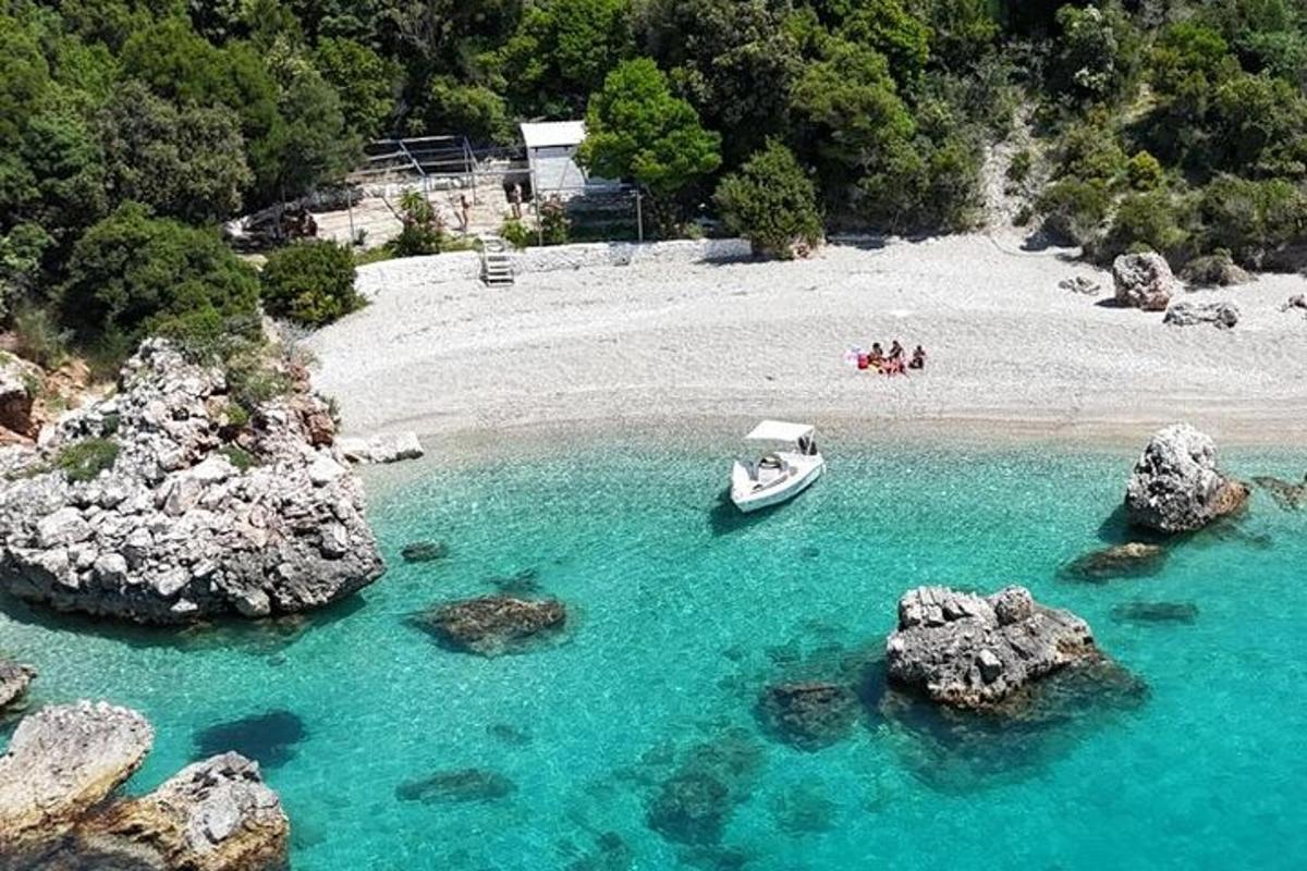a boat in the water near a beach with rocks
