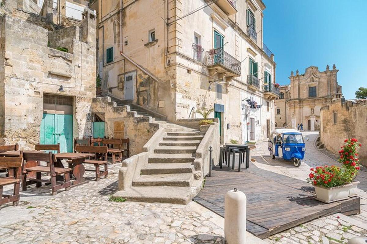 eine Gasse mit Treppen und Tischen und einem blauen Fahrzeug