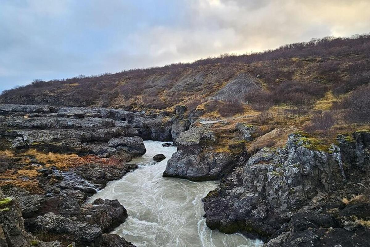 řeka na skalnatém svahu s horou