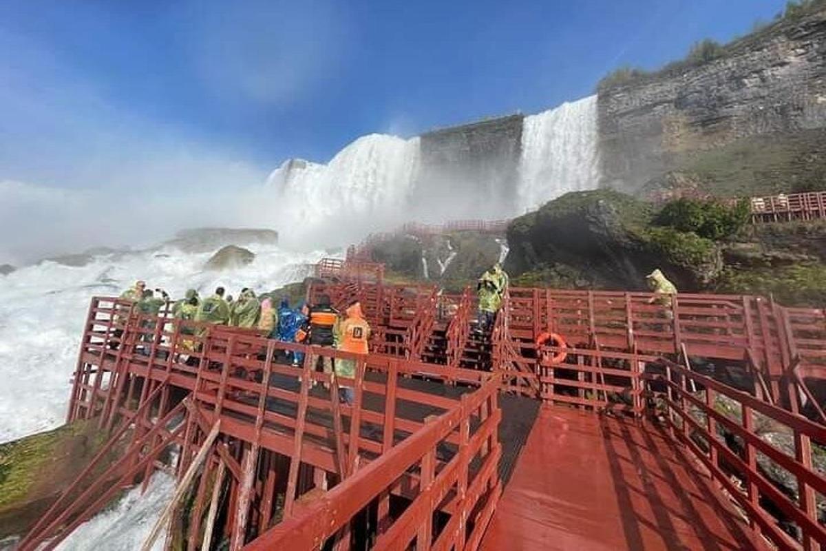 a group of people standing on a bridge near a waterfall