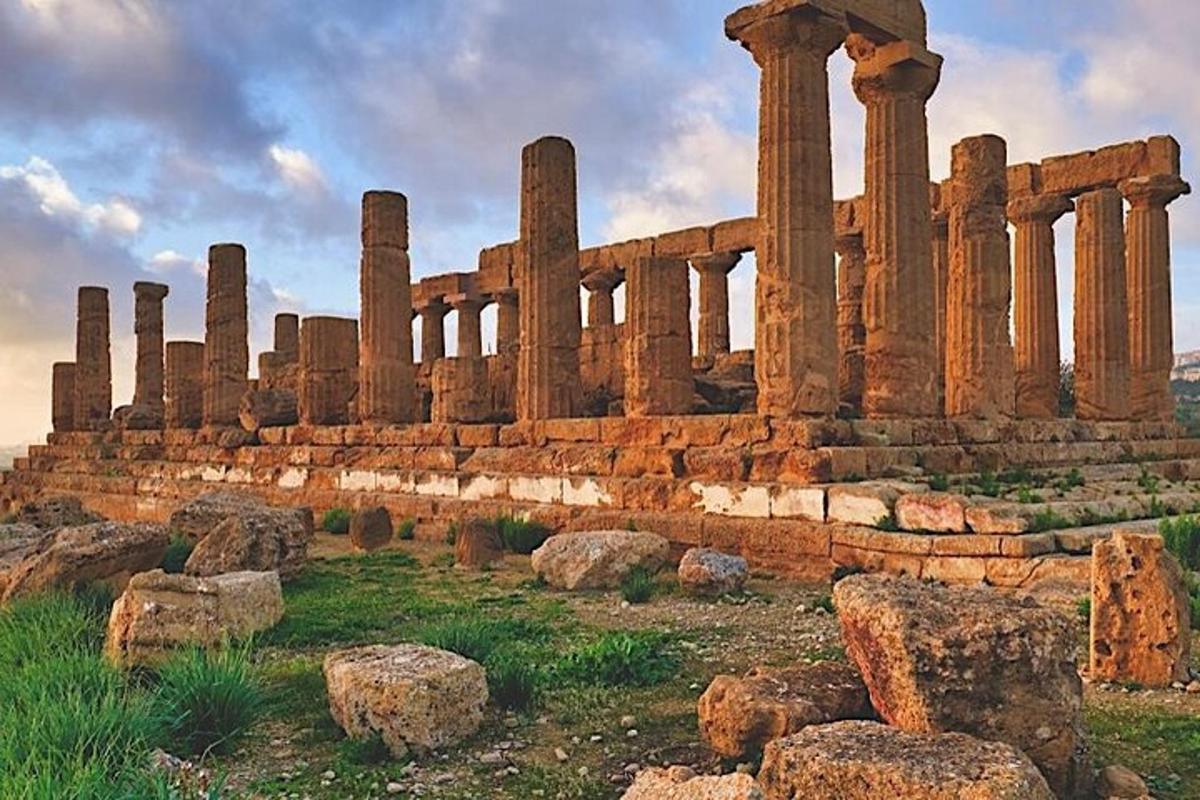 Un edificio antiguo con columnas en un campo con rocas.