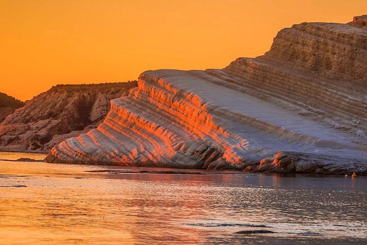 Un iceberg en el agua con una puesta de sol de fondo