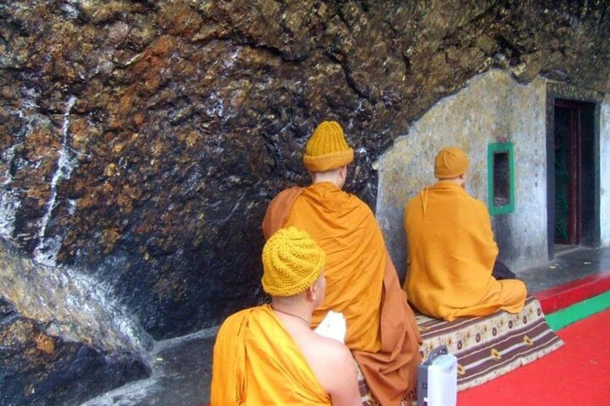 three monks sitting in front of a waterfall