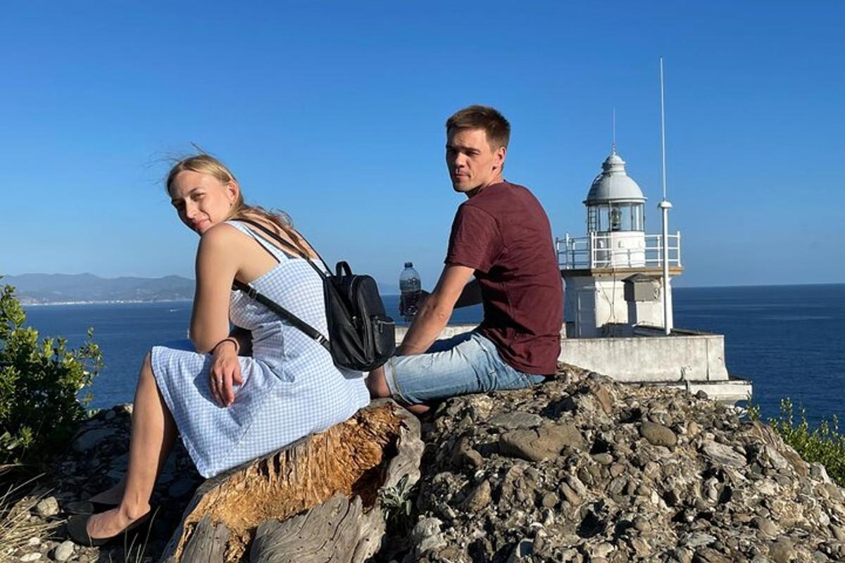 un uomo e una donna seduti su una roccia con un faro