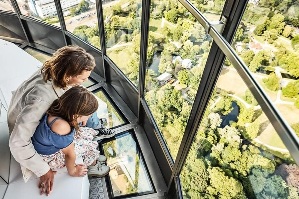 Una mujer y una niña mirando la vista desde lo alto de una torre de cristal.