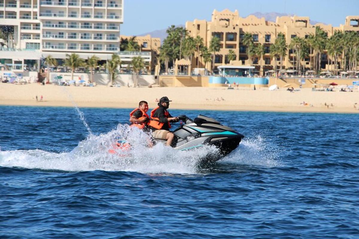 două persoane care călăresc un jet ski în apă lângă o plajă