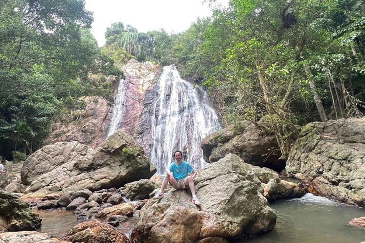 seseorang yang duduk di atas batu di hadapan air terjun
