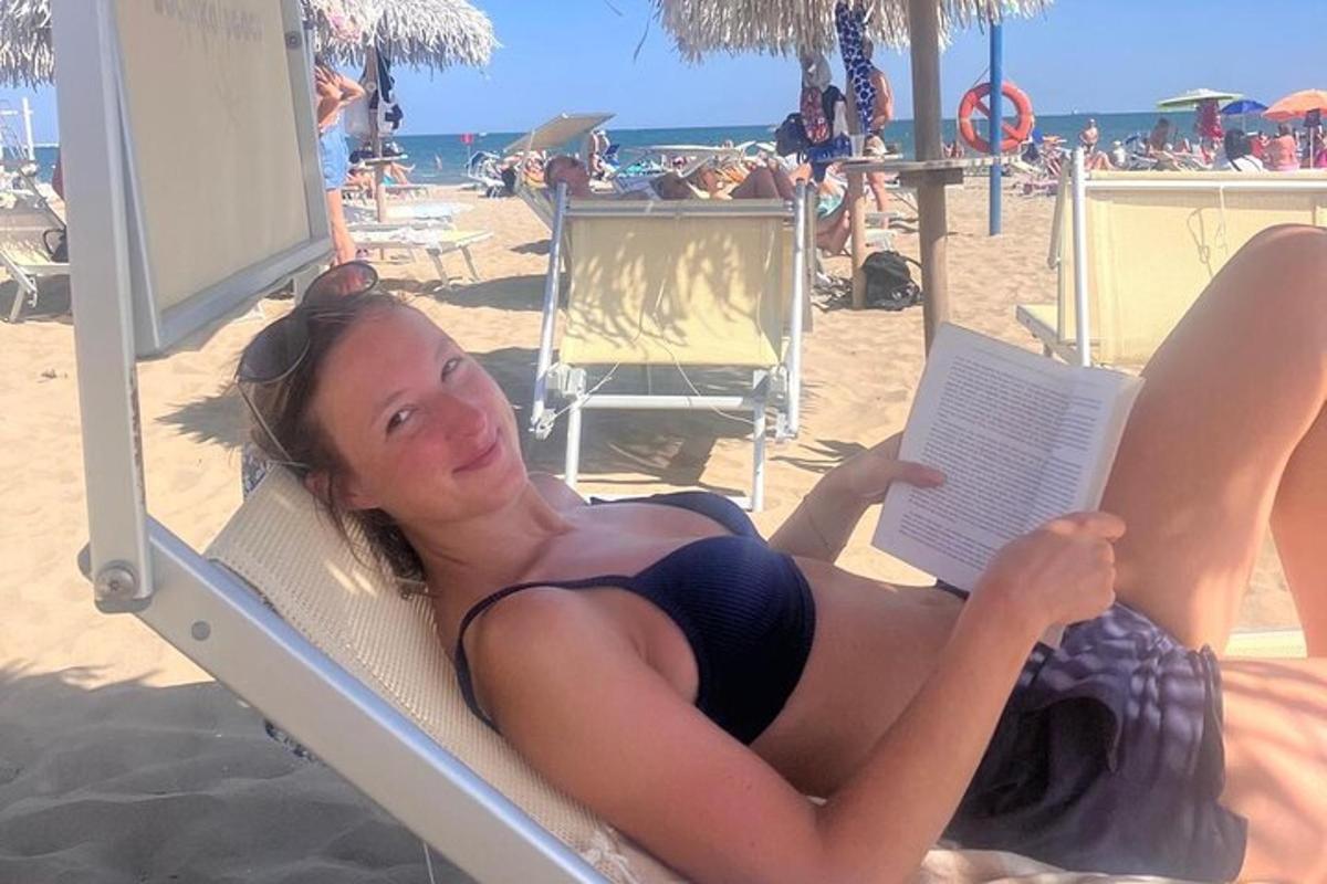 Una mujer tumbada en la playa leyendo un libro