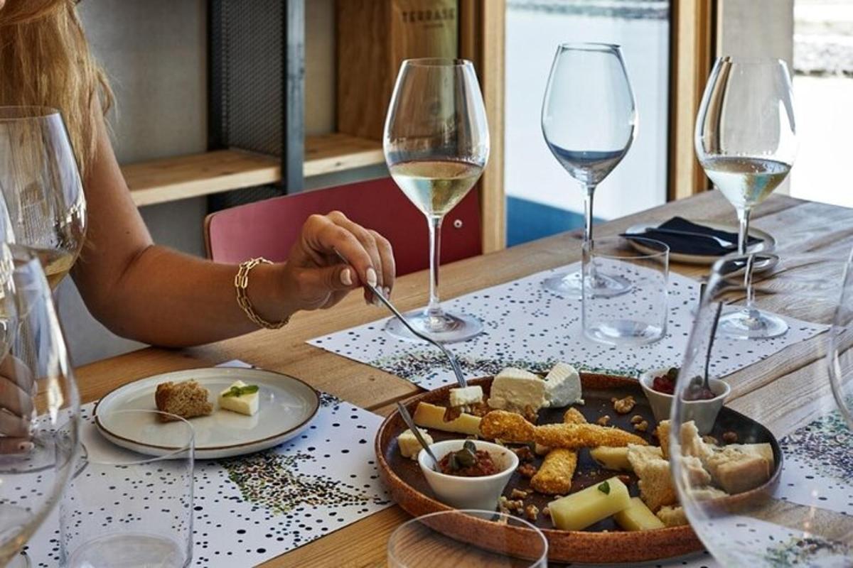 osoba sedící u stolu s talířem jídla a sklenicemi na víno