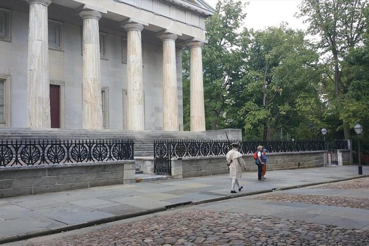 двоє людей йдуть тротуаром перед будівлею