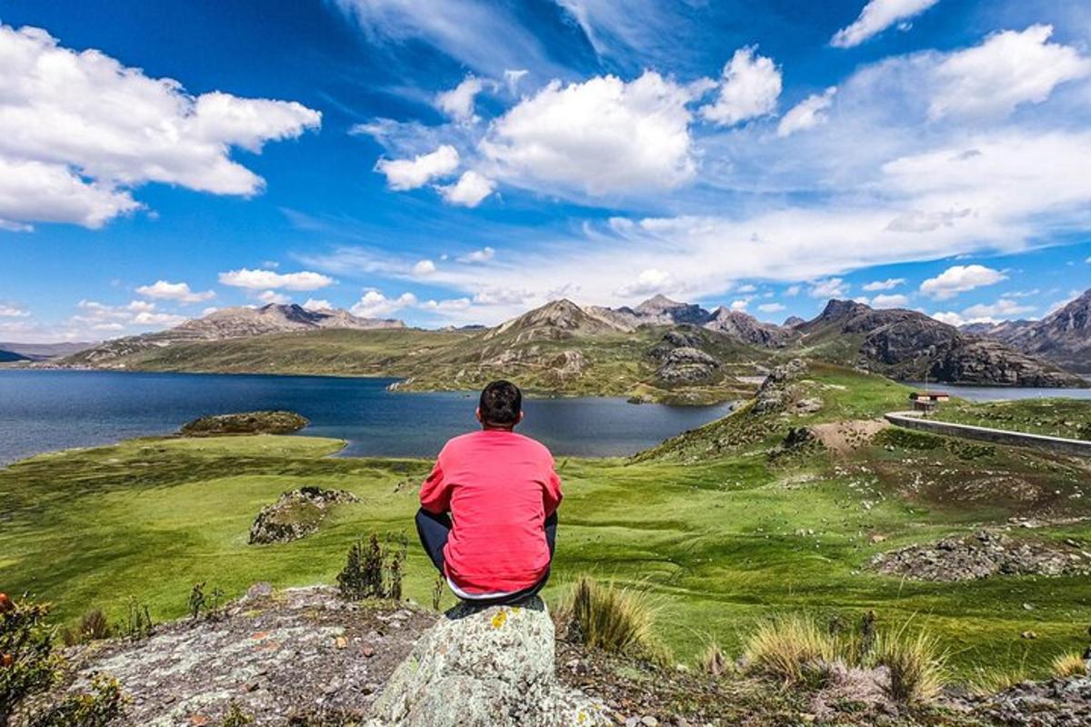 Ein Mann sitzt auf einem Felsen und schaut auf einen See