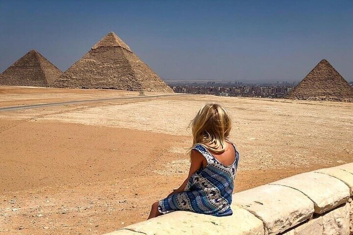 فتاة صغيرة تجلس على حافة وتنظر إلى الأهرامات