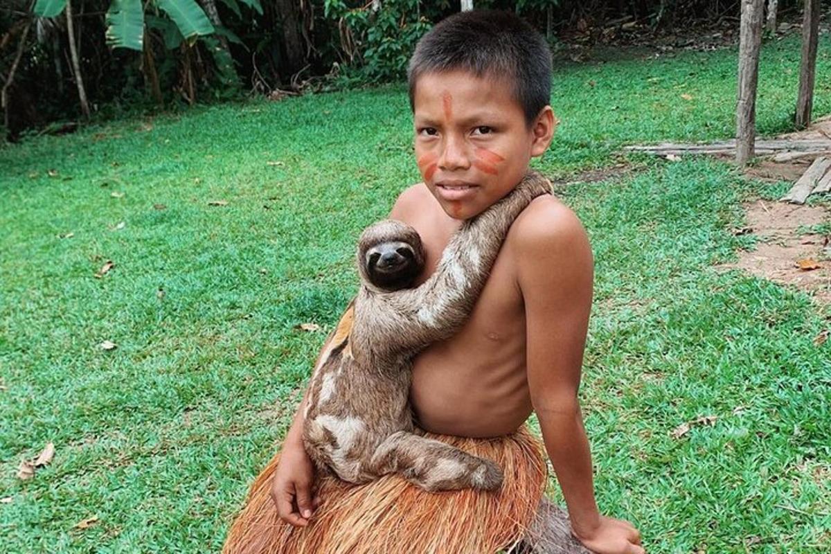 um menino segurando um filhote de animal em um tronco