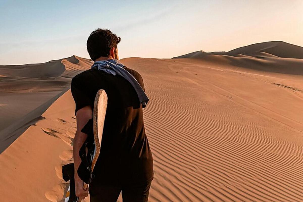 un uomo in piedi nel deserto che tiene in mano una tavola da surf