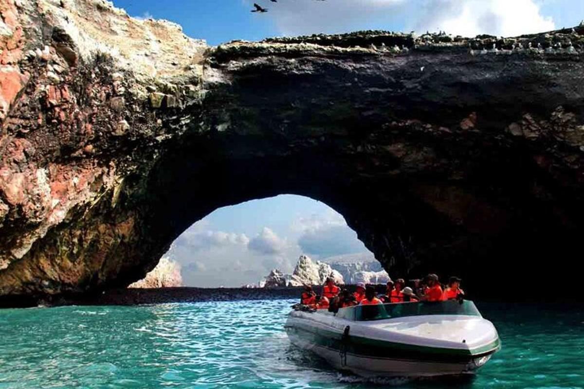 um grupo de pessoas em um barco em frente a uma caverna