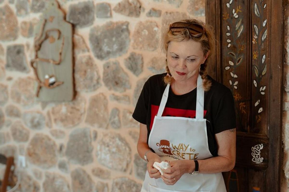 una donna con un grembiule bianco in piedi accanto a un muro