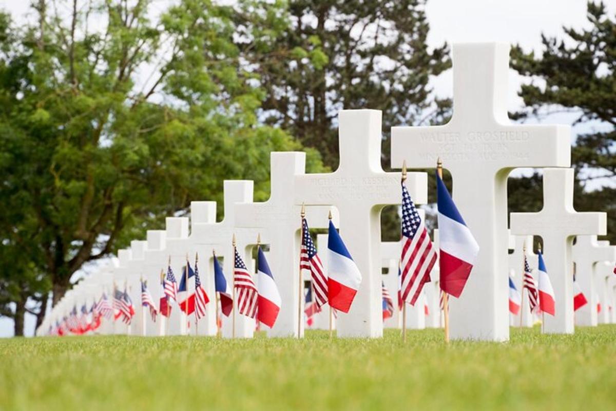 a row of white crosses with american flags in a field