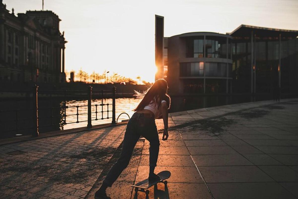 Žena jede na skateboardu po chodníku