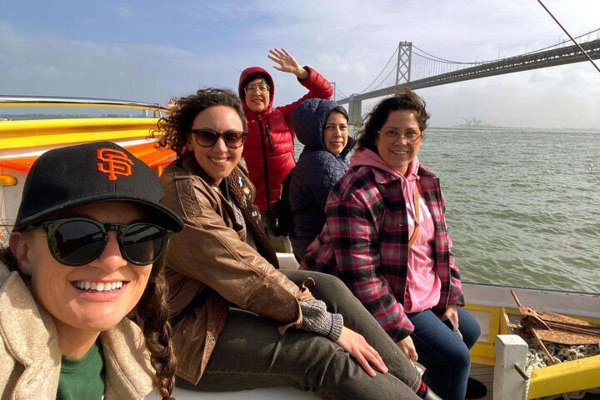 um grupo de mulheres em um barco em frente à ponte Golden Gate