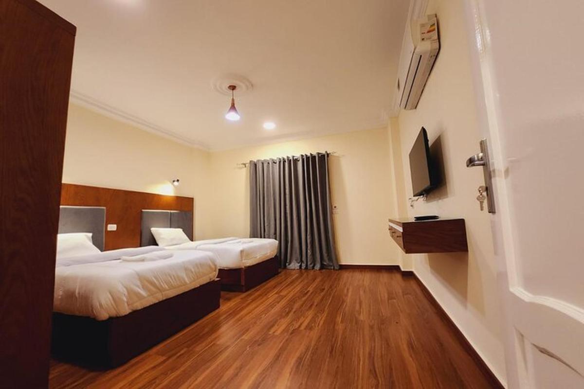 egy hotelszoba két ággyal és egy televízióval