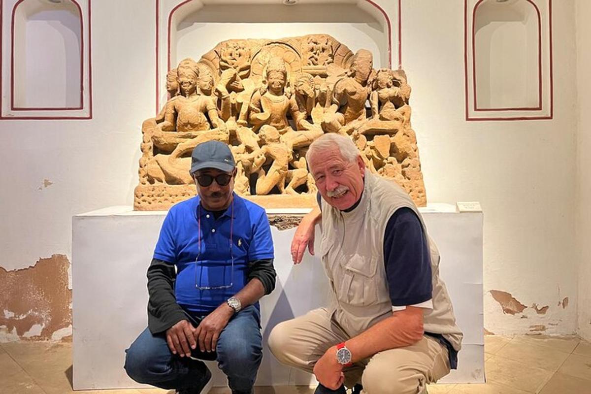 two men sitting in front of a sculpture in a museum