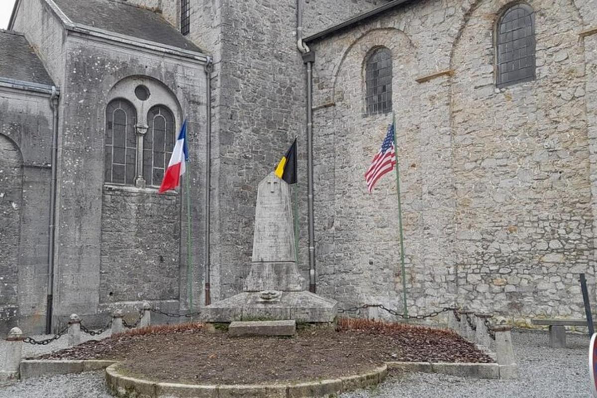un monument în fața unei biserici cu două steaguri