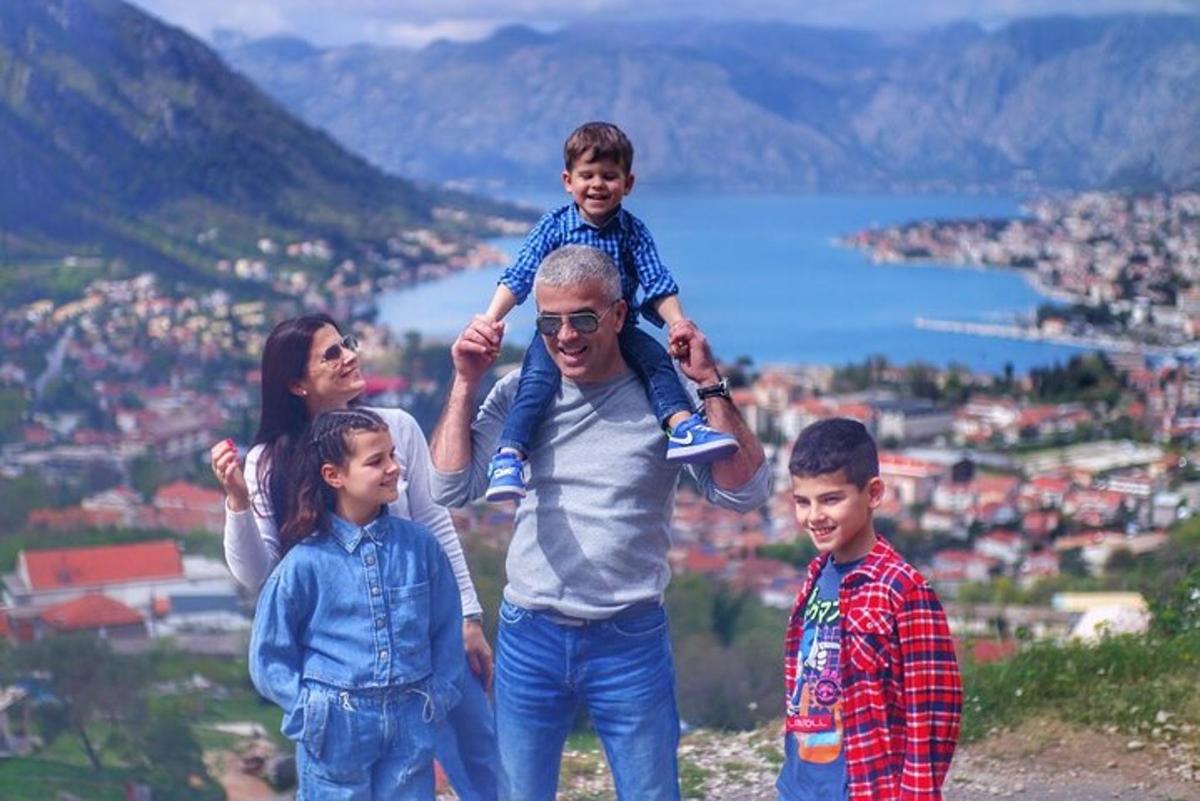Човек и двоје деце стоје на врху планине