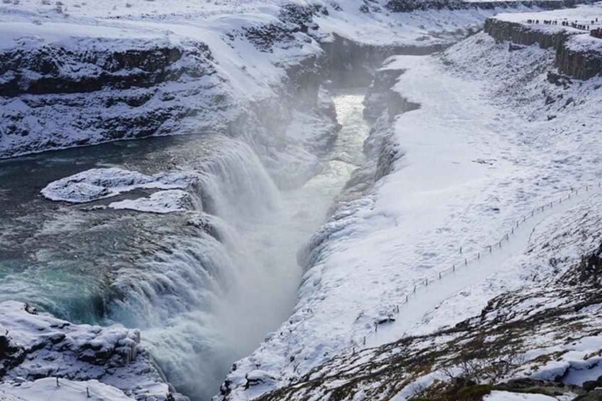 uma cachoeira com neve na encosta de uma montanha
