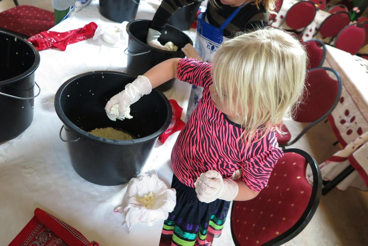 a little girl is putting food in a pot