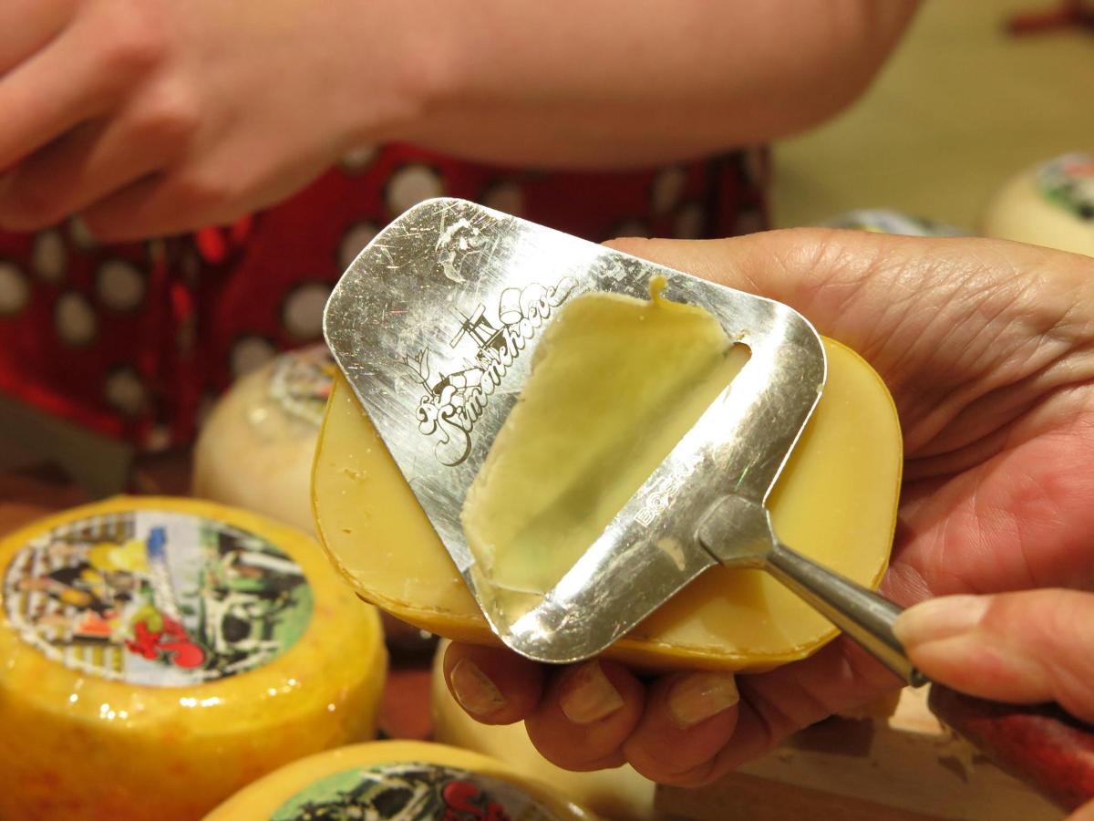 osoba držící špachtli nad kusem sýra