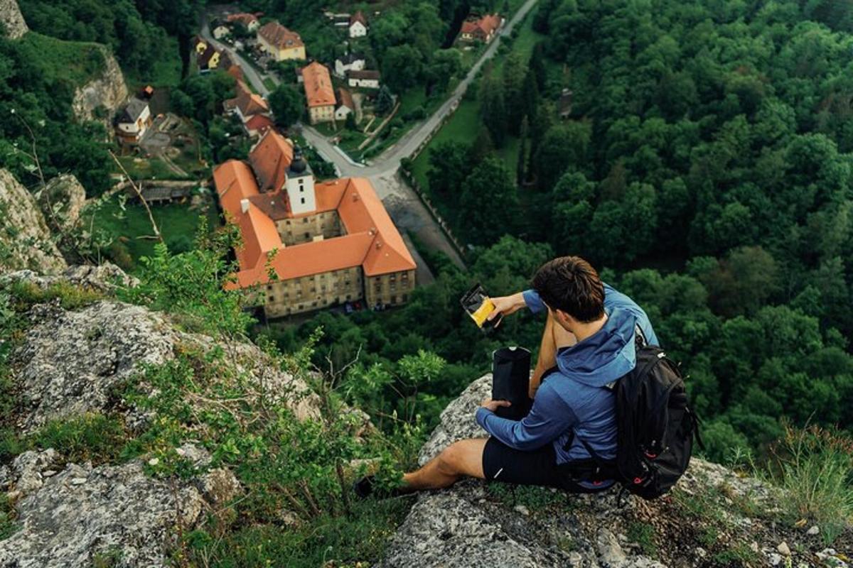 muž sedící na skále a fotící dům