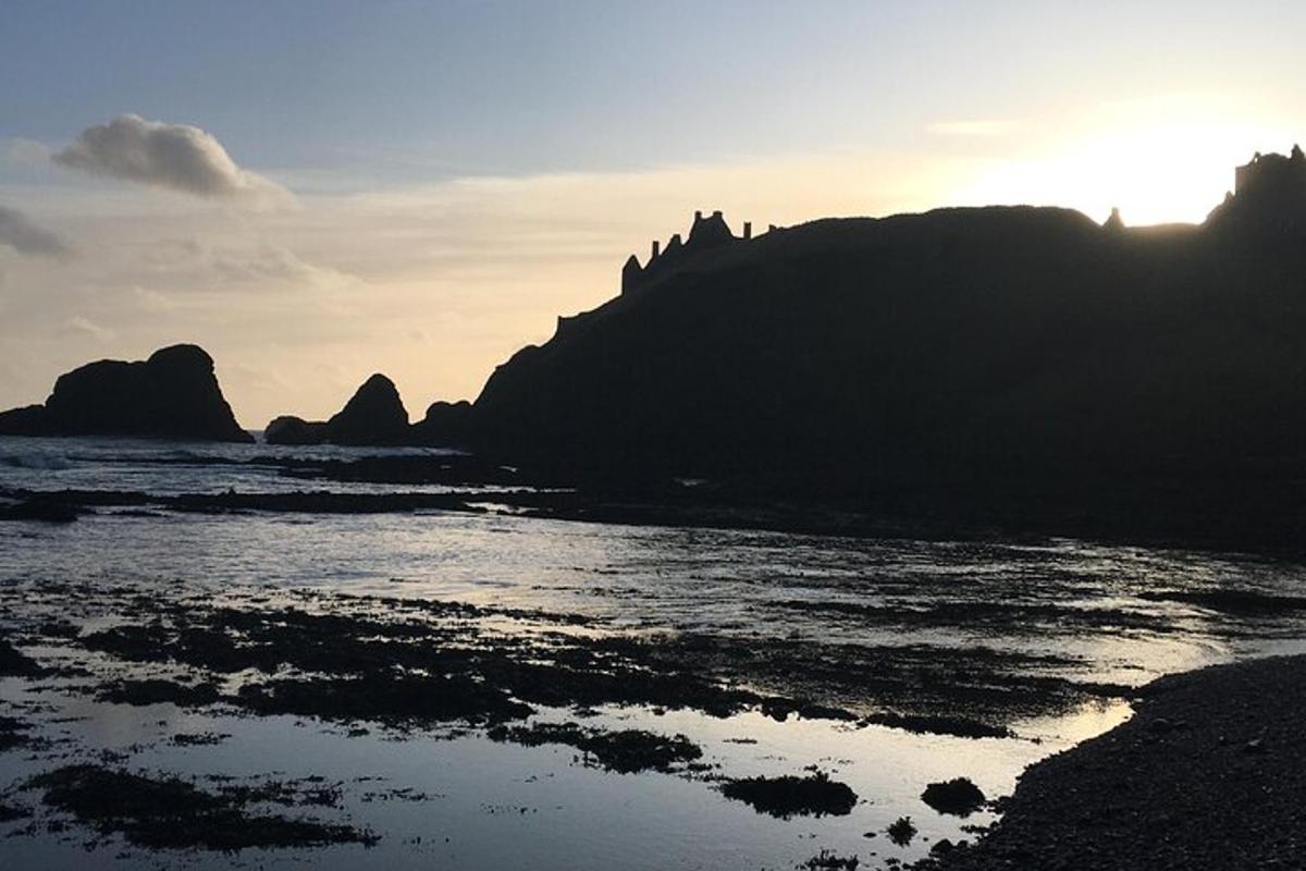 un tramonto su una spiaggia con rocce nell'acqua