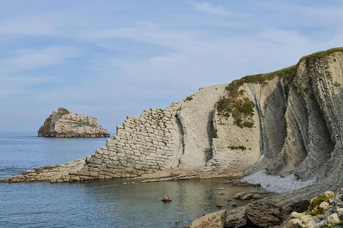 duża ściana skalna w wodzie obok oceanu