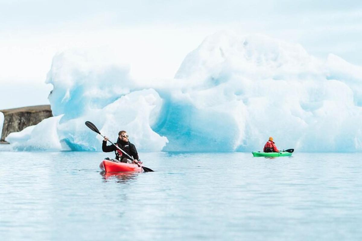 two people kayaking in the water next to an iceberg