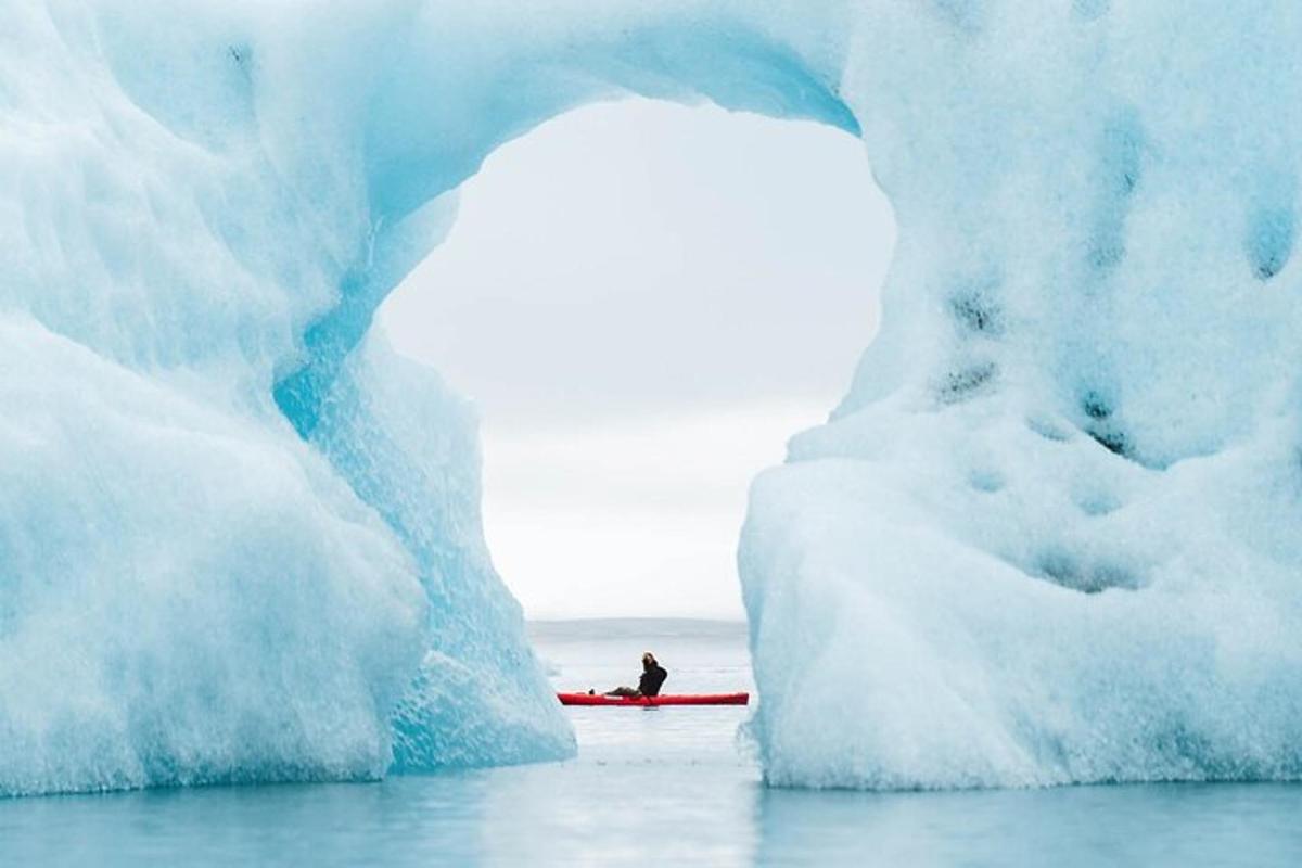 a person in a kayak in front of an iceberg
