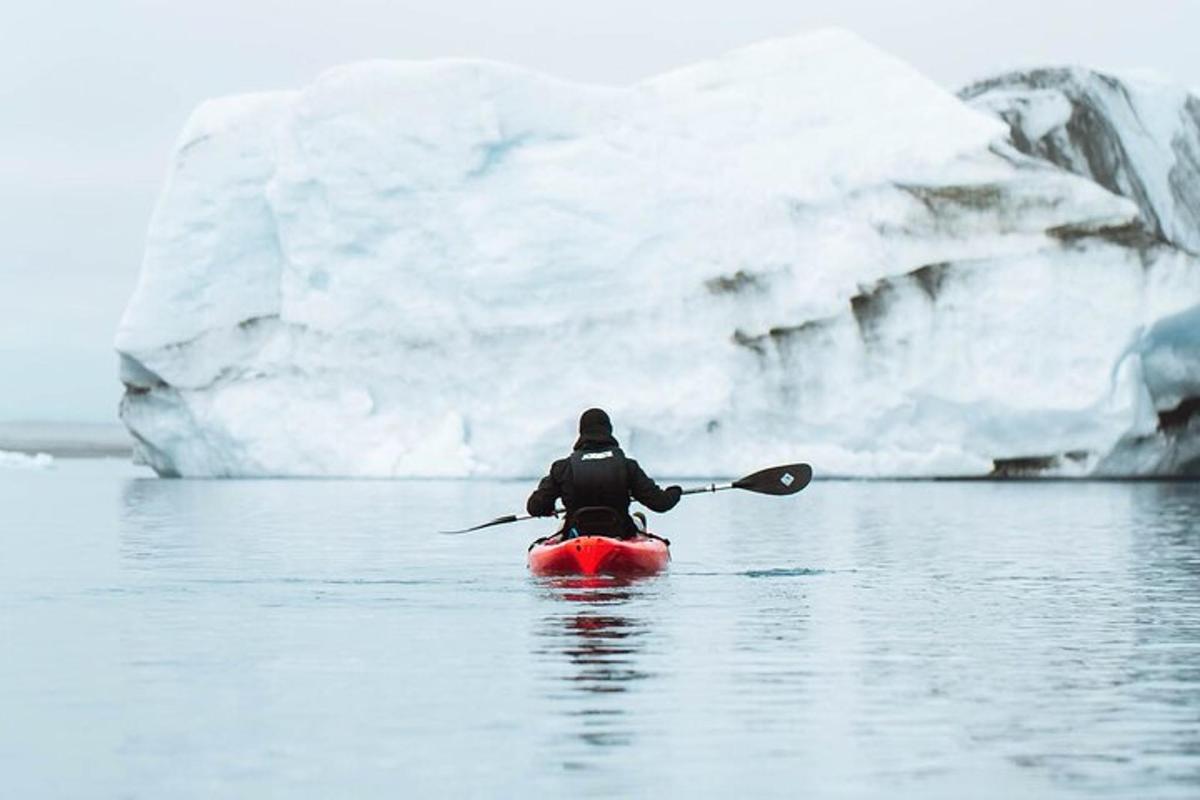 a person in a kayak in front of an iceberg