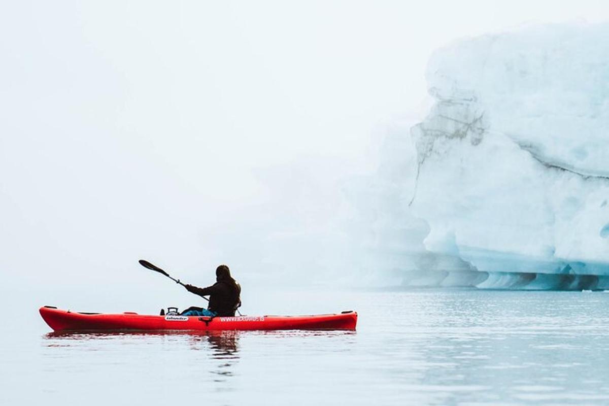 a person in a kayak in front of an iceberg