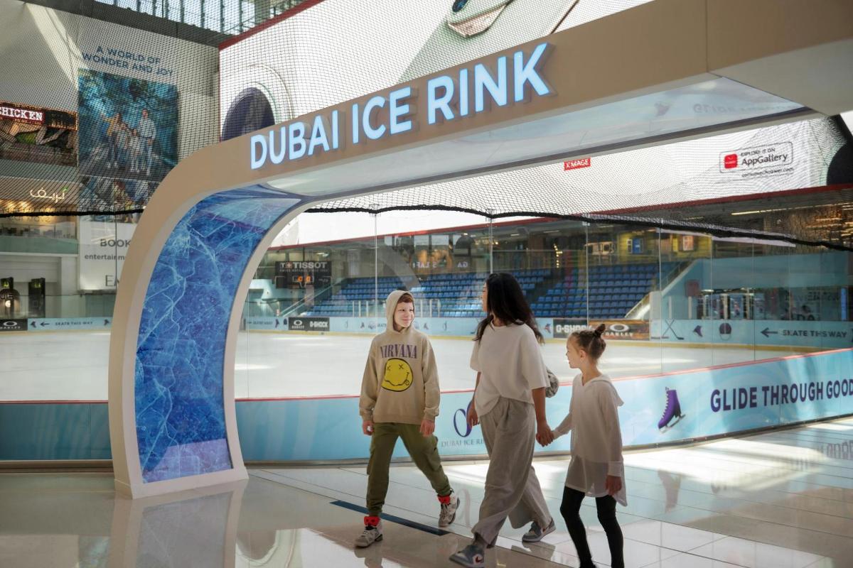 a woman and two children walk through a display at a dallas ice rink
