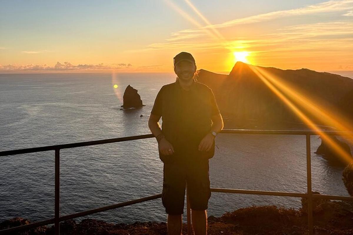 un uomo in piedi di fronte all'oceano al tramonto