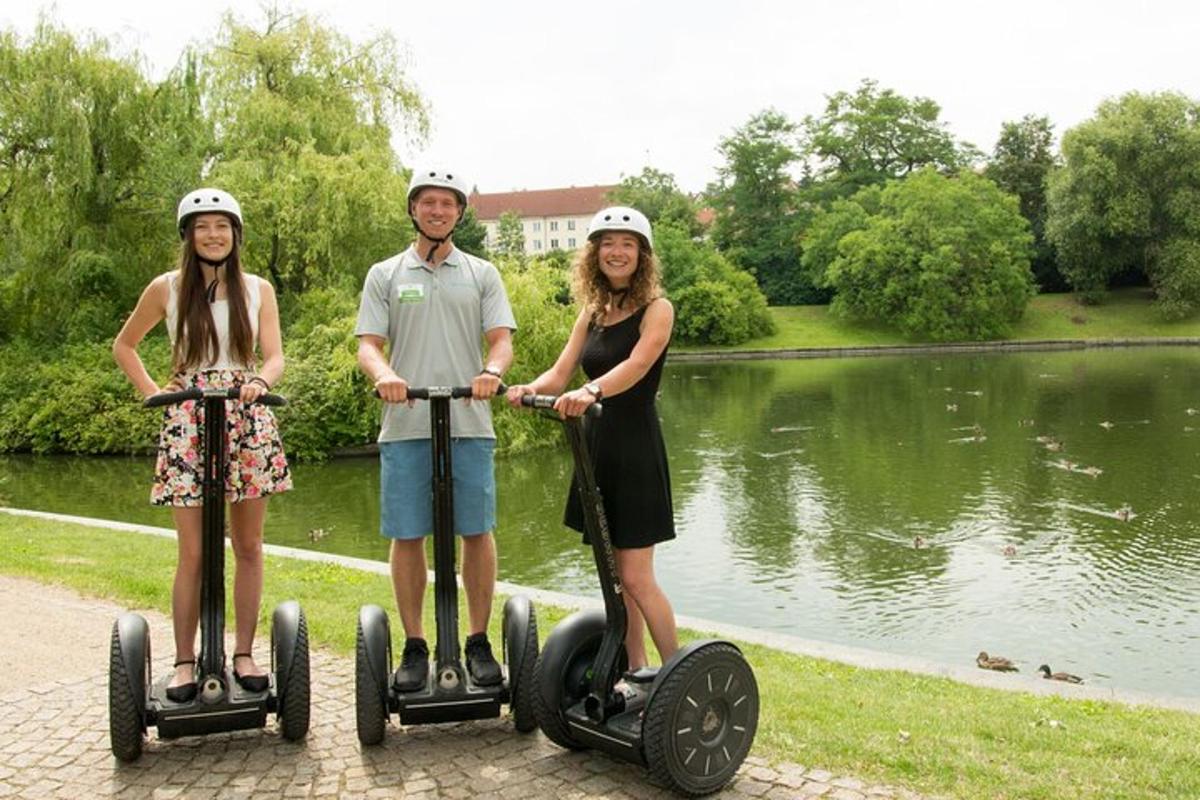 muž a dvě ženy jedoucí na segwayích u jezera