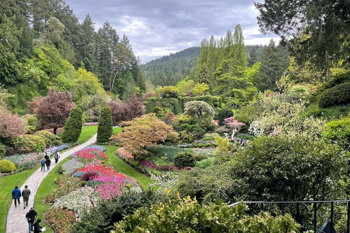 Menschen gehen durch einen Garten mit Blumen und Bäumen