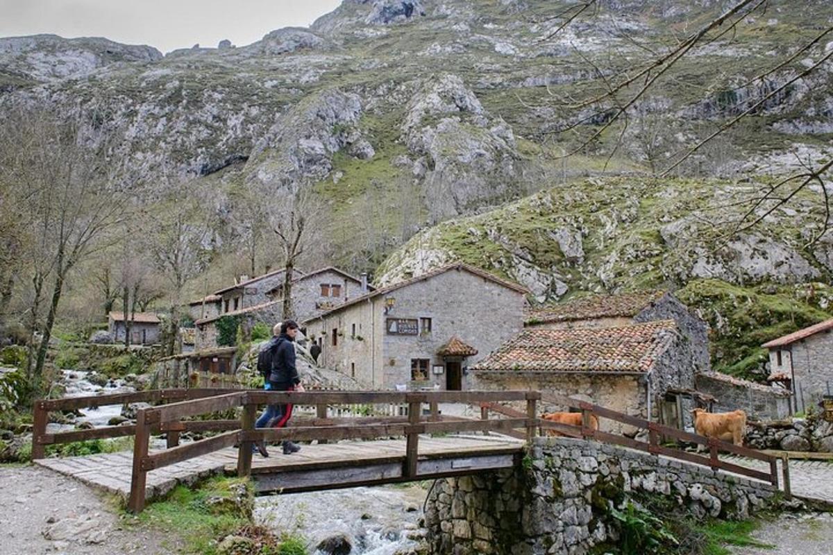 a man walking across a wooden bridge over a village