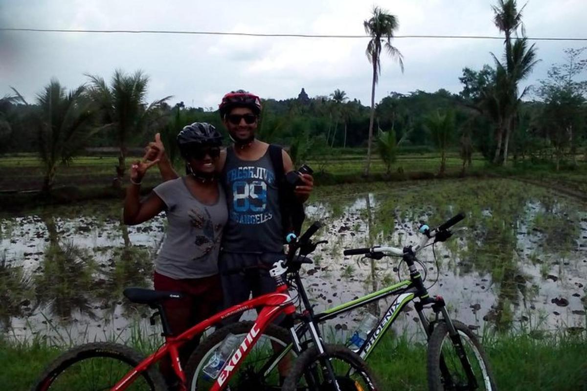 duas pessoas em pé ao lado de bicicletas em frente a um campo de arroz