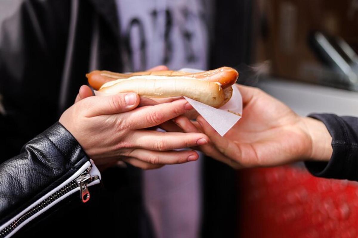 inimene, kes hoiab käes hot dogi
