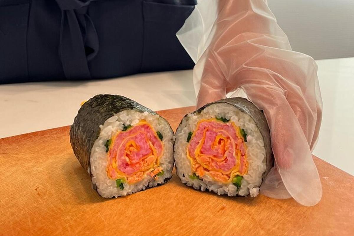 osoba držící dvě sushi rolky na prkénku