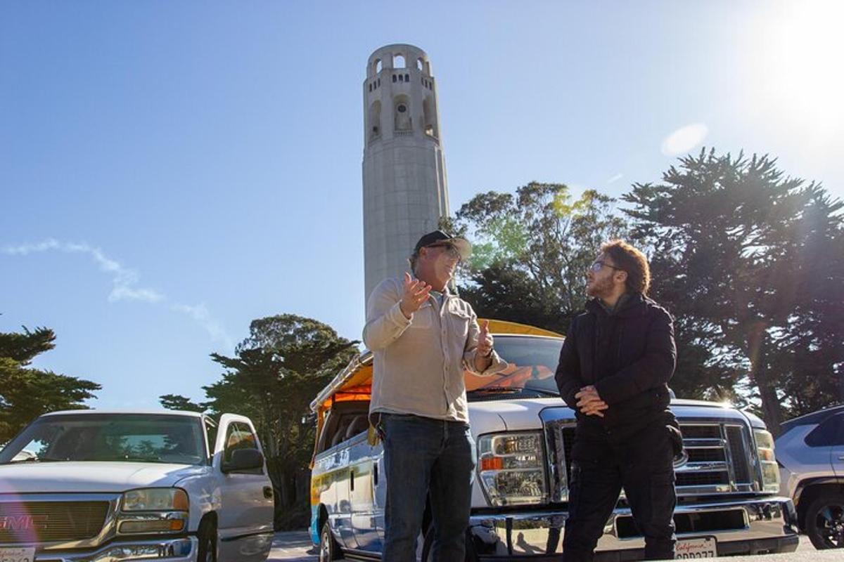 dois homens parados em um estacionamento com um farol ao fundo
