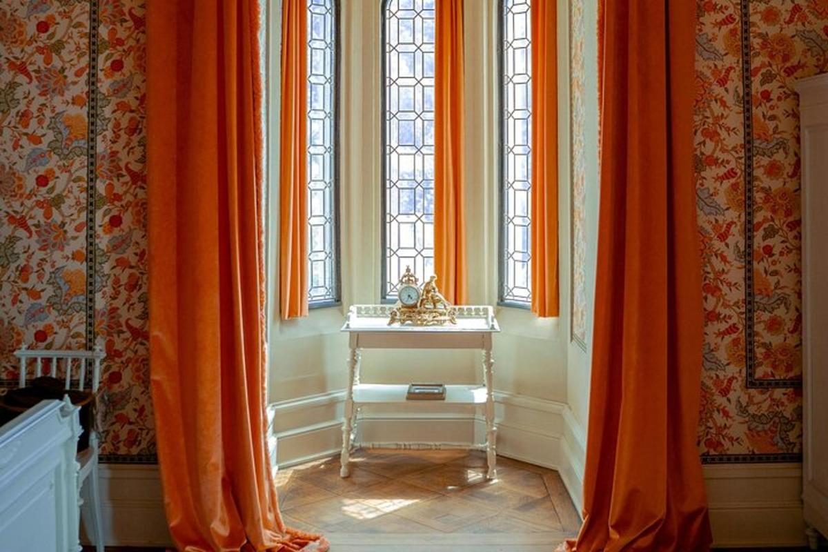 Una habitación con cortinas naranjas y una mesa y ventanas.