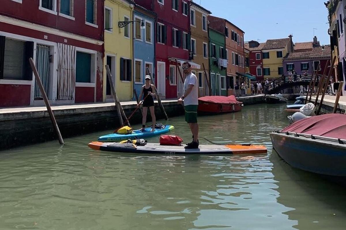 two people are standing on paddle boards in a canal